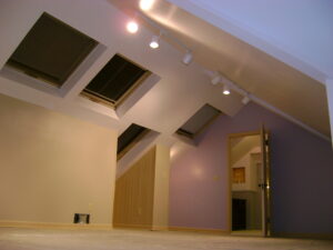 Finished attic living space featuring skylights, recessed lighting, hardwood floors, and custom drywall finishing by Absolute Building Concepts in the Kansas City Metro.