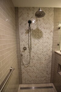 Walk-in custom tile shower with frameless glass installed during a bathroom remodel.