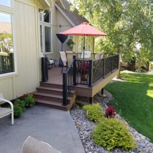 Composite backyard deck with composite railing, outdoor furniture, and patio umbrella, creating a comfortable outdoor living space.