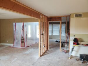 Interior wall opened during a home remodeling project to expose structural framing, wall studs, electrical wiring, and framing members before renovation work continues.
